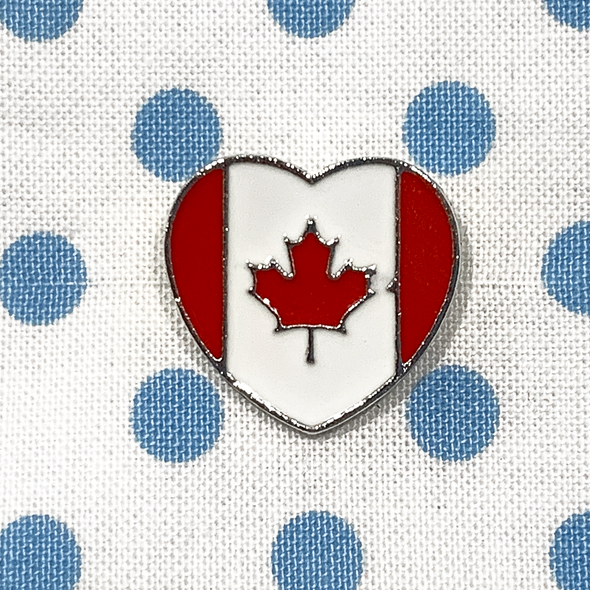 Red and white enamel on heart shaped silver metal Canadian flag pin on blue polka dot fabric project bag by Pretty Warm Designs