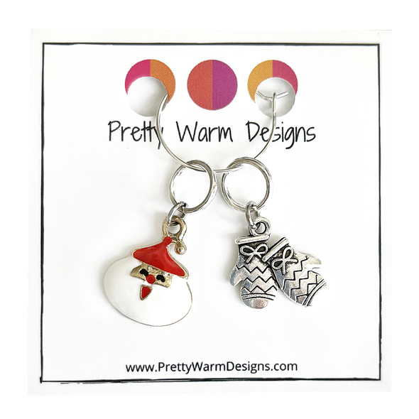 Two Christmas-themed knitting ring stitch markers, one red and white Santa and one silver toned mittens attached with silver hoop ring to cardstock with Pretty Warm Designs text and logo