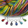Set of six coloured rhinestones in red, pink, purple, blue, turquoise and green set in silver toned snag free ring stitch markers for knitting by Pretty Warm Designs and variegated skein of yarn in yellow, green, blue, pink, red and purple