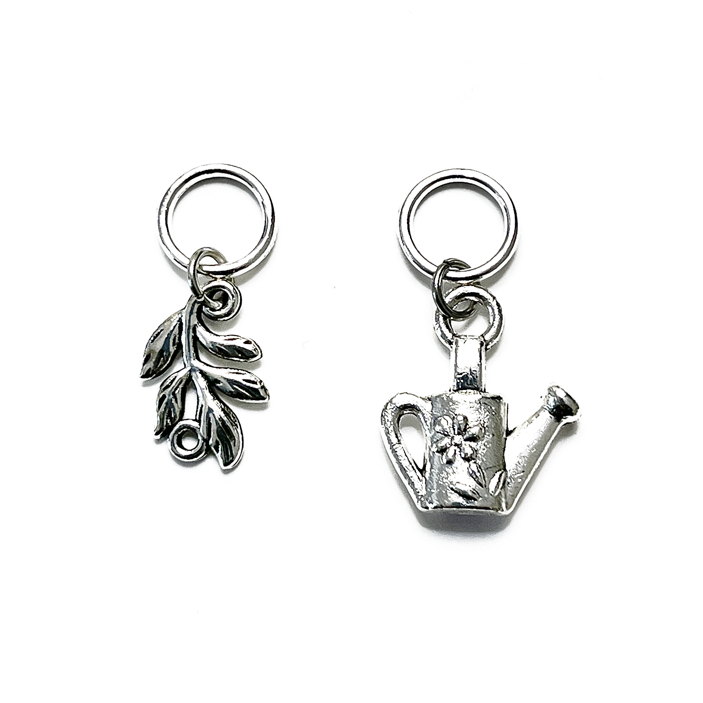 One antiqued silver leaf branch and one antiqued silver watering can snag free ring stitch markers for knitting by Pretty Warm Designs Inc