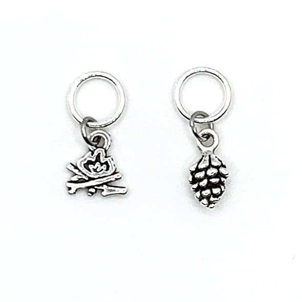 Two antiqued silver stitch markers, one camp fire and one pine cone for knitting by Pretty Warm Designs