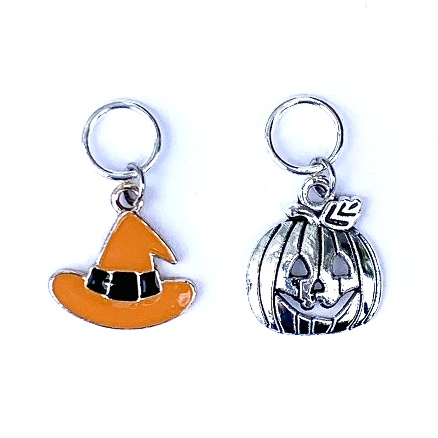 Two Hallowe'en-themed knitting ring stitch markers, one orange and black enamel witch hat and one silver toned jack-o-lantern by Pretty Warm Designs