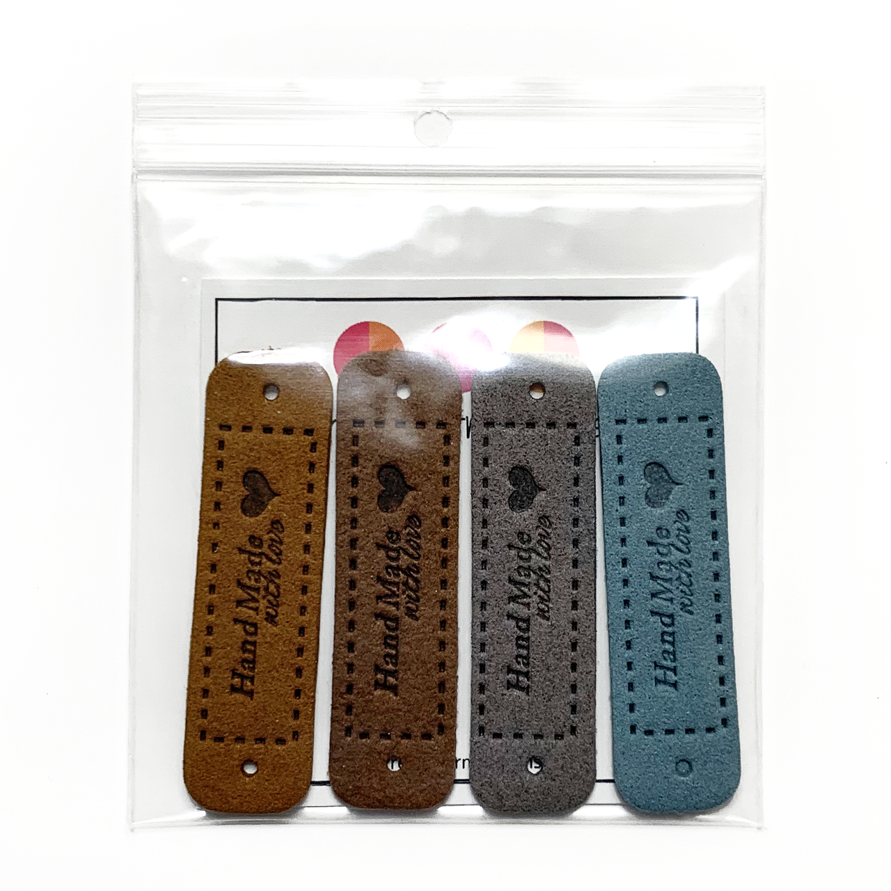 Four medium brown, dark brown, grey and teal coloured PU polyurethane vegan leather garment label tags for knitted and crocheted items sold by Pretty Warm Designs Inc.