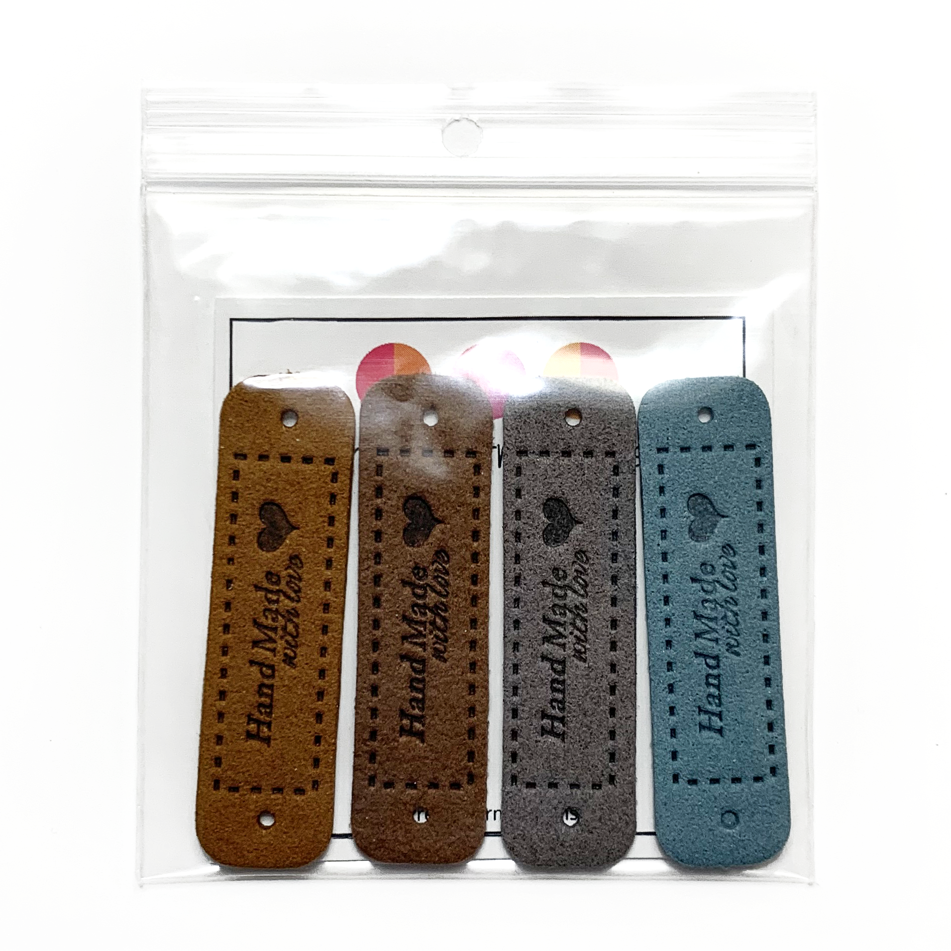 Four medium brown, dark brown, grey and teal coloured PU polyurethane vegan leather garment label tags for knitted and crocheted items sold by Pretty Warm Designs Inc.