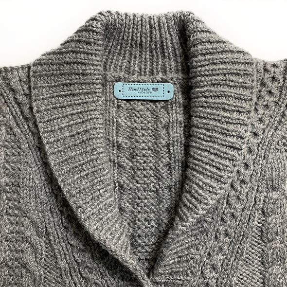 Grey hand knitted wool sweater with teal PU polyurethane leather garment tag sold by Pretty Warm Designs Inc.