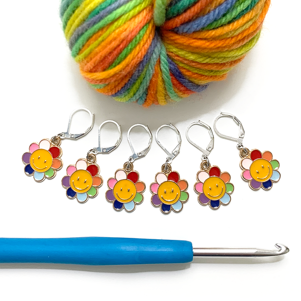 Set of six yellow and rainbow petal enamel happy face flower charms locking stitch markers with rainbow variegated yarn and hook for crochet by Pretty Warm Designs