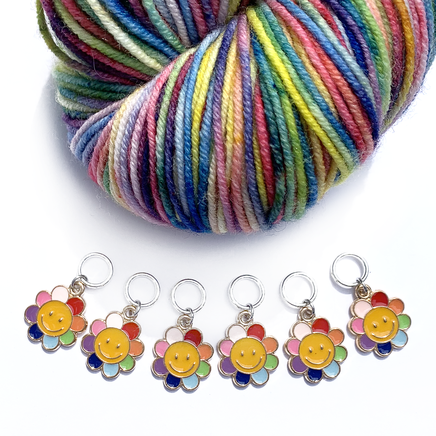 Set of six yellow and rainbow petal enamel happy face flower charms snag free ring stitch markers with variegated yarn for knitting by Pretty Warm Designs