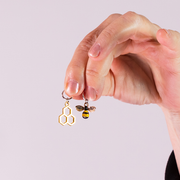 Hand holding honeycomb and bee stitch markers by Pretty Warm Designs