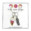 Two summer-themed knitting ring stitch markers, one enamel pink and brown ice cream cone and one silver toned flip flop attached with a silver hoop ring to cardstock with Pretty Warm Designs text and logo