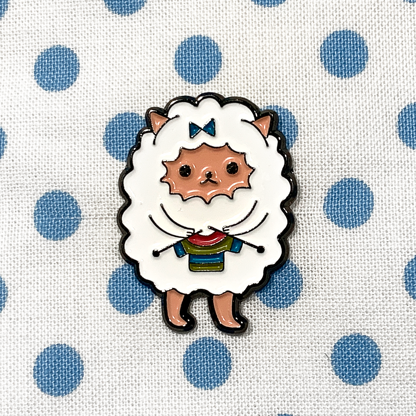 White and multicoloured enamel on black background sweater knitting sheep brooch pin on blue polka dot fabric bag by Pretty Warm Designs