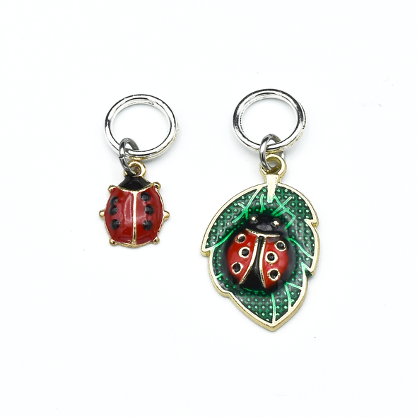 One red and black ladybug and one red and black ladybug on a green leaf enamel charms ring knitting stitch markers by Pretty Warm Designs 