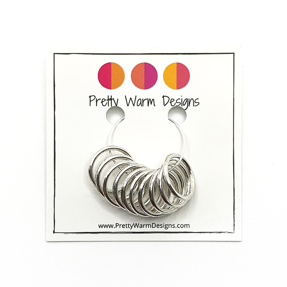 10 large ring silver plated stitch markers attached to card stock with Pretty Warm Designs logo and text