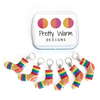 Set of six large rainbow coloured resin charm stitch markers for knitting and decorative tin with Pretty Warm Designs logo