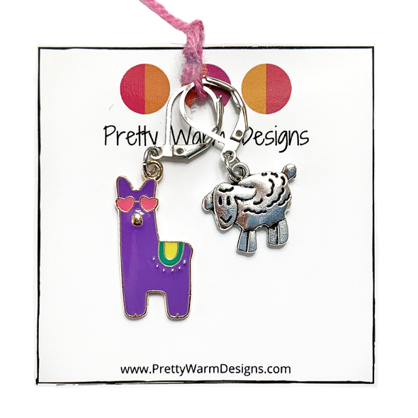 Purple enamel llama crochet stitch marker with pink heart eyes and yellow and green accents plus antique silver lamb locking crochet stitch marker attached with pink yarn to cardstock with Pretty Warm Designs logo and URL sold by Pretty Warm Designs Inc.
