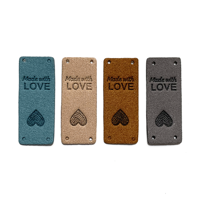 Four teal, tan, medium brown and grey coloured PU polyurethane vegan leather garment label tags for knitted and crocheted items sold by Pretty Warm Designs Inc.