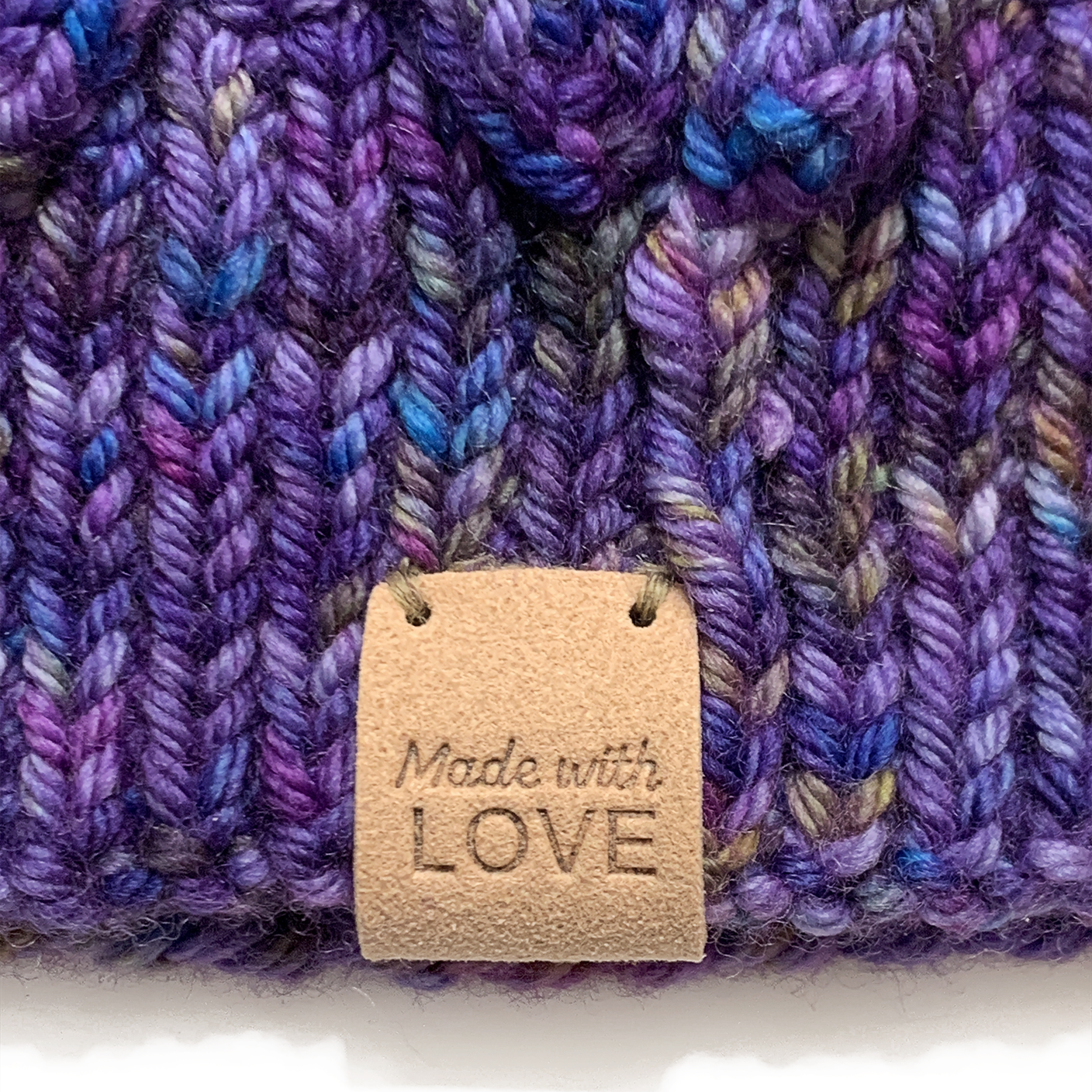 Tan PU polyurethane leather Made With Love garment label tag sewn onto purple lace knitted hat, sold by Pretty Warm Designs Inc.