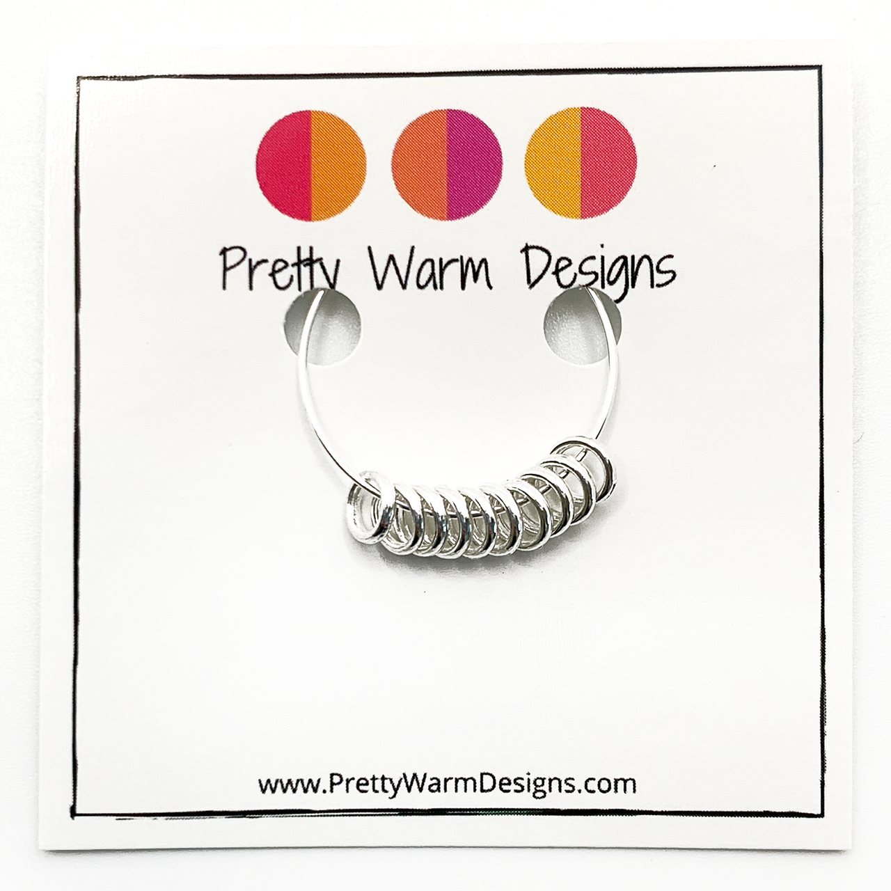 Set of 10 snag free mini silver toned ring stitch markers for knitting attached to card stock with Pretty Warm Designs text and logo