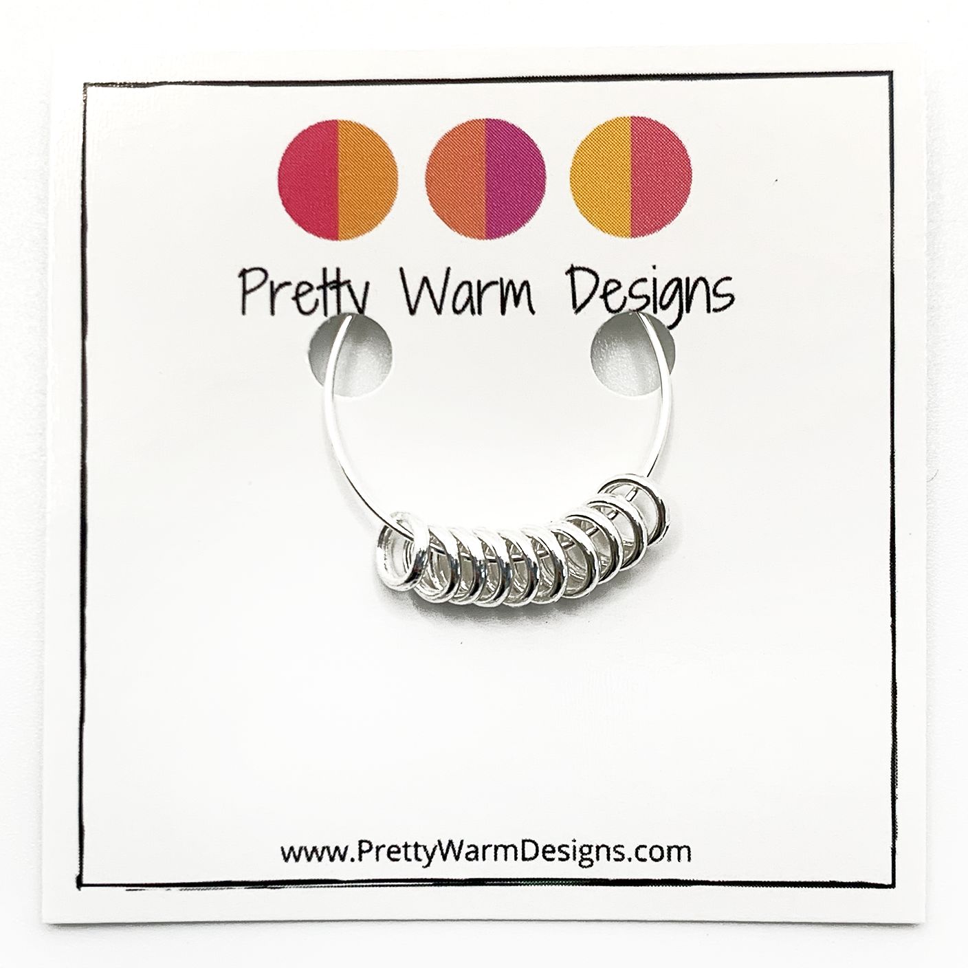 Set of 10 snag free mini silver toned ring stitch markers for knitting attached to card stock with Pretty Warm Designs text and logo