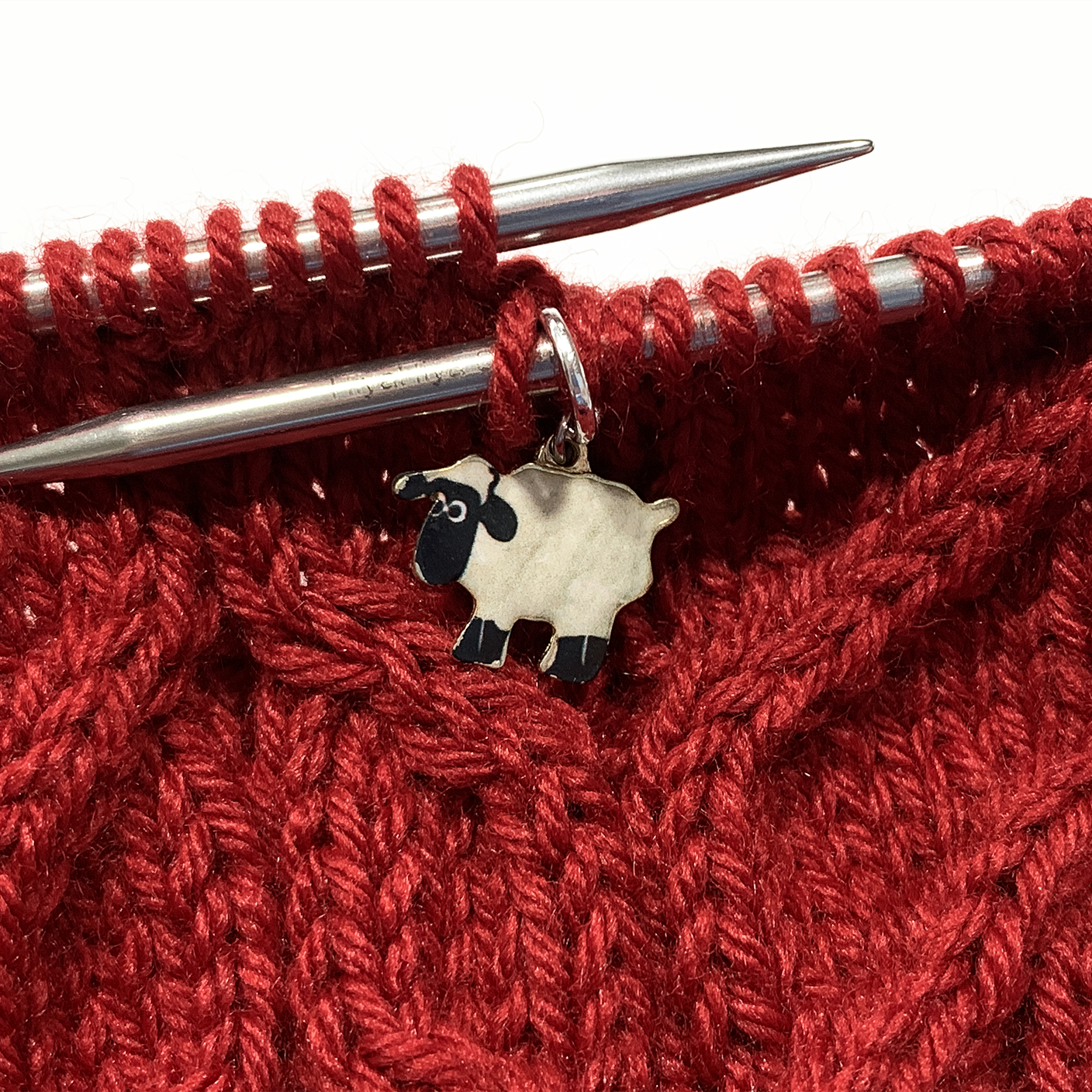 Sheep stitch marker on circular knitting needle — snag free ring style marker shown in use on cable knit project