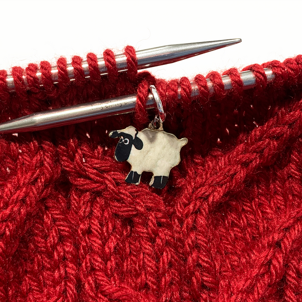 Enamel white and black sheep charm snag free ring stitch marker on knitting needles with red cabled yarn swatch by Pretty Warm Designs