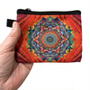 Hand holding small multicoloured mandala screen printed fabric zipper pouch sold by Pretty Warm Designs Inc.