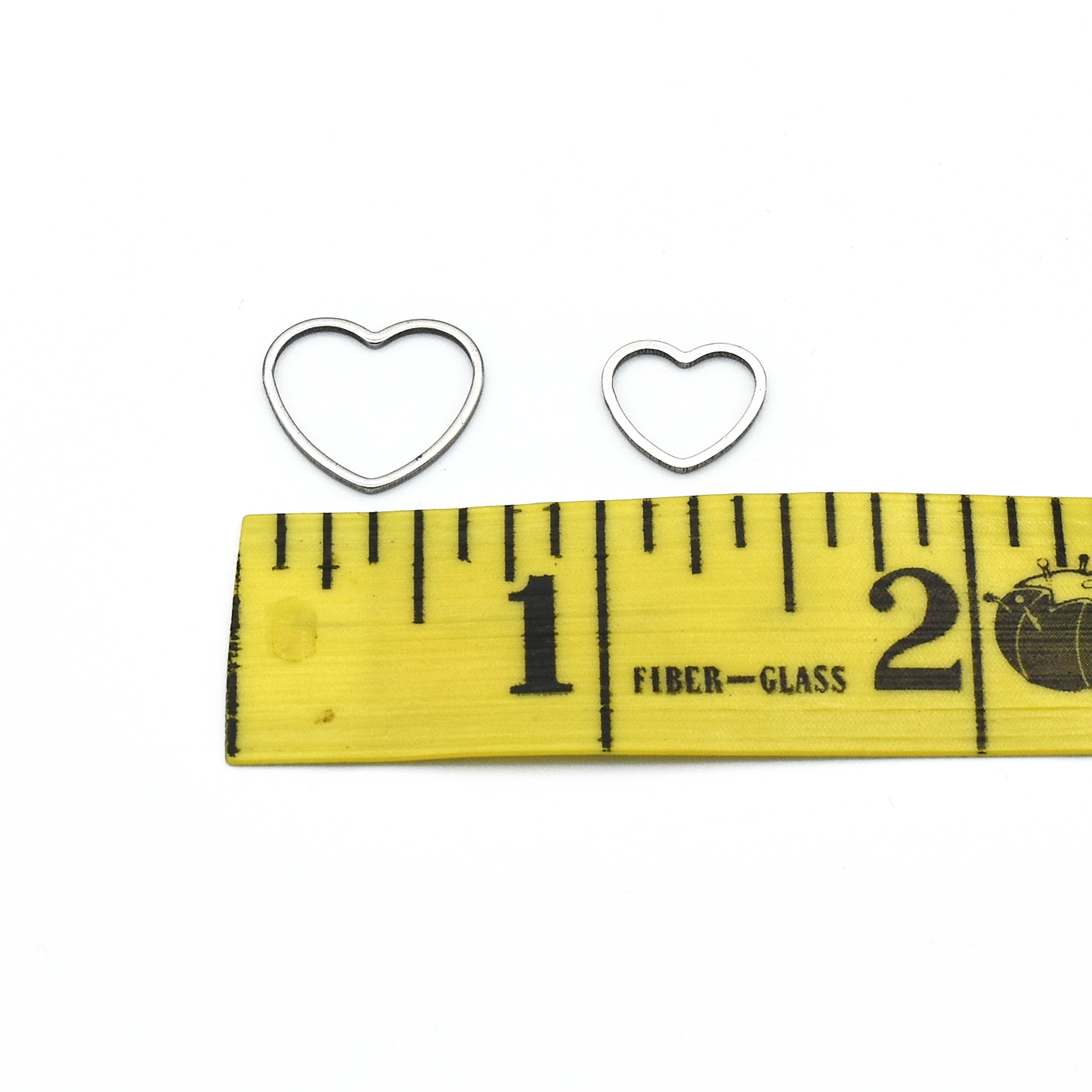 Large and small heart silver toned ring knitting stitch markers above measuring tape by Pretty Warm Designs