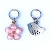 Two spring-themed knitting ring stitch markers, one pink enamel cherry blossom and one small silver song bird by Pretty Warm Designs