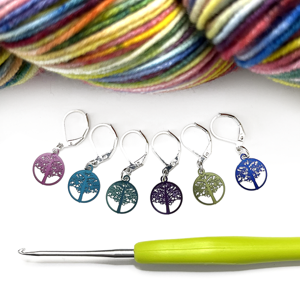 Six colour coated stainless steel round tree of life charm locking stitch markers for crochet with green handled crochet hook and multicoloured variegated yarn by Pretty Warm Designs Inc