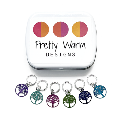 Six colour coated stainless steel round tree of life charm snag free ring stitch markers for knitting and decorative storage tin with Pretty Warm Designs logo by Pretty Warm Designs Inc