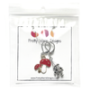 One red and white enamel toadstool crochet stitch marker and one antiqued silver gnome crochet stitch marker attached to silver ring hanging from white cardstock printed with Pretty Warm Designs logo and website URL packaged in a clear poly bag