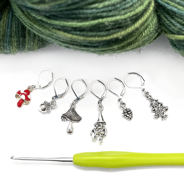 Set of five antiqued silver charm crochet stitch markers and one enamel toadstool charm locking crochet stitch markers with green yarn and crochet hook for crochet by Pretty Warm Designs
