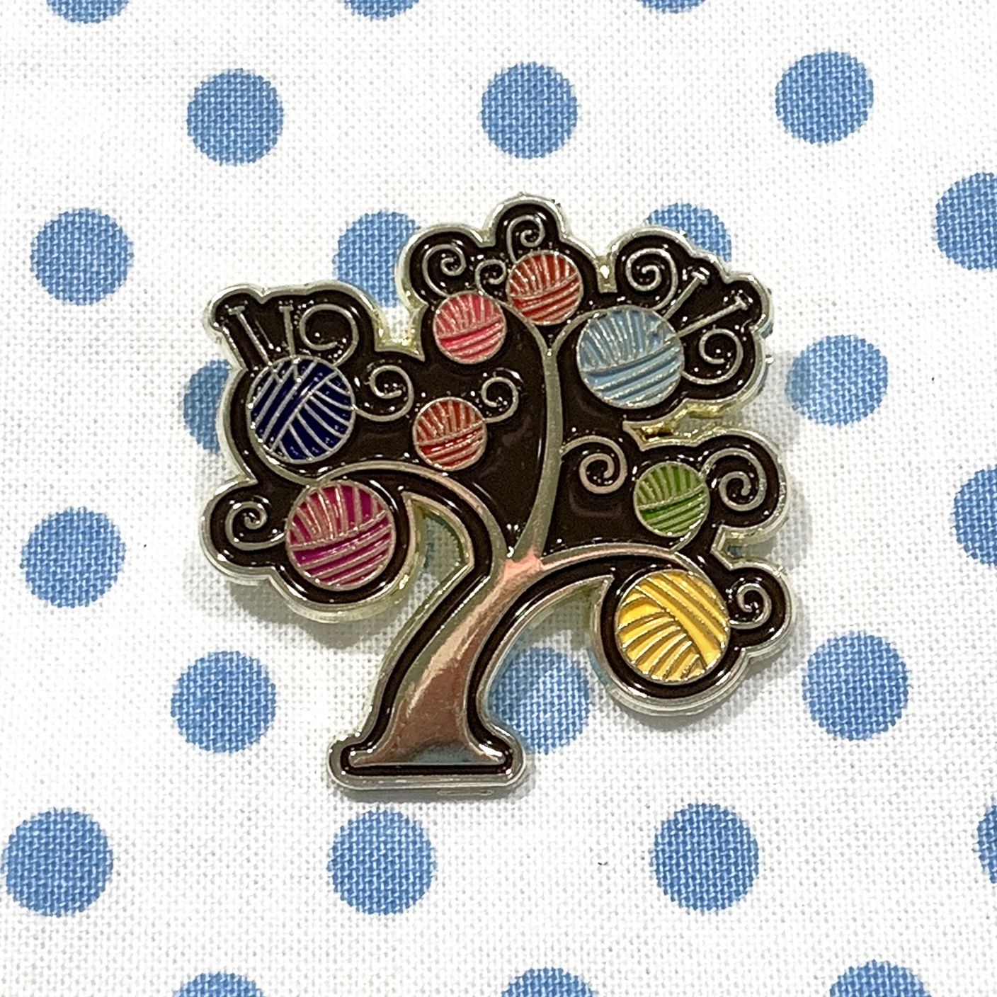 Multicoloured enamel on gold metal yarn tree pin on blue polka dot project bag by Pretty Warm Designs